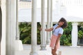 Pretty afro american woman standing next to column smiling