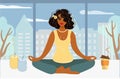 Pretty afro woman meditating while sitting at home. A girl in a lotus position with a beautiful view - big city life and