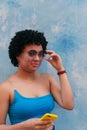 Pretty afro woman wearing a blue blouse laughing in front of a blue background. She is looking at the camera Royalty Free Stock Photo