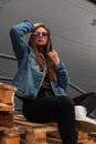 Pretty american young hipster woman in trendy casual youth clothes in stylish purple glasses poses outdoors in the city. Modern Royalty Free Stock Photo