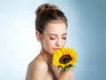 Pretty as a petal. Studio shot of a beautiful young woman smelling a sunflower. Royalty Free Stock Photo