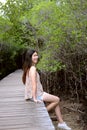 Pretty Asain girl is smiling and sitting on wooden bridge in the tropical mangrove forest. Royalty Free Stock Photo