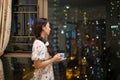 Pretty Asia university female students driink tea or wine near window with blurred bokeh colorful City light background Royalty Free Stock Photo