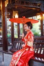 Young, beautiful and elegant Chinese woman wearing a typical Chinese bride`s silk red dress, adorned with golden phoenix and drago Royalty Free Stock Photo