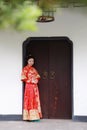 Young, beautiful and elegant Chinese woman wearing a typical Chinese bride`s silk red dress, adorned with golden phoenix and drago Royalty Free Stock Photo