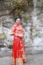 Young, beautiful and elegant Chinese woman wearing a typical Chinese bride`s silk red dress, adorned with golden phoenix and drago Royalty Free Stock Photo