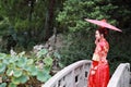 Young, beautiful and elegant Chinese woman wearing a typical Chinese bride`s silk red dress, adorned with golden phoenix and drago Royalty Free Stock Photo