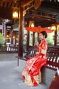 Young, beautiful and elegant Chinese woman wearing a typical Chinese bride`s silk red dress, adorned with golden phoenix and drago Royalty Free Stock Photo