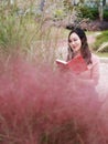 Pretty Asian Chinese woman girl feel freedom dream pray flower field fall park grass lawn hope nature read book knowledge educate Royalty Free Stock Photo