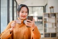 A pretty Asian female holding a smartphone and a credit card, using an online mobile banking Royalty Free Stock Photo