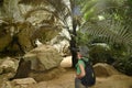 Pretty Asian female looks through binoculars at the entrance of a Hup Pa Tat cave.