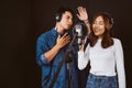 Pretty Asian female and male singer recording songs by using a studio microphone and pop shield on mic with passion in music Royalty Free Stock Photo