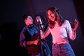 Pretty Asian female singer recording songs by using a studio microphone and pop shield on mic with male playing guita. Royalty Free Stock Photo