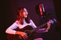 Pretty Asian female singer recording songs by using a studio microphone and pop shield on mic while playing guitar. Royalty Free Stock Photo