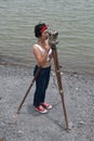 Pretty Asian female surveyor or engineer worker working with theodolite transit equipment.