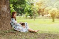 Pretty asian girl in vintage dress sitting leaning against on the tree relaxing.Vintage tone Royalty Free Stock Photo