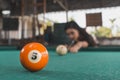 A pretty asian lady playing a game of nine ball pool aiming for the number 5 ball. At an open air and old billiard hall Royalty Free Stock Photo