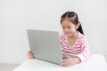 Pretty asian little child girl sitting at desk and using laptop computer stay at home Royalty Free Stock Photo