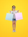 Pretty Asian little child girl wearing sunglasses holding shopping bags on yellow isolated background with clipping path. Full Royalty Free Stock Photo