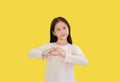 Pretty Asian little girl gesture finger Heart symbol isolated on yellow background with clipping path. Kid expression hand to Love