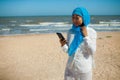 Pretty asian muslim woman looking at mobile phone on the beach. Royalty Free Stock Photo