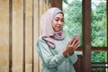 Pretty asian muslim woman with veil holding mobile phone Royalty Free Stock Photo