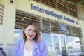 A pretty asian traveler or tourist in a lavender blazer in front of the International arrivals area of an airport