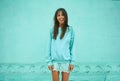 pretty asian woman in blue sweatshirt with long darke hair smiling over blue background