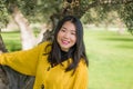 Pretty Asian woman in city park - lifestyle portrait of young beautiful and happy Chinese girl playful by a tree enjoying enjoying Royalty Free Stock Photo