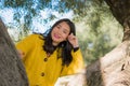 Pretty Asian woman in city park - lifestyle portrait of young beautiful and happy Chinese girl playful by a tree enjoying enjoying Royalty Free Stock Photo