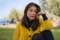 Pretty Asian woman in city park - lifestyle portrait of young beautiful and happy Chinese girl sitting on green grass cheerful and Royalty Free Stock Photo