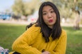 Pretty Asian woman in city park - lifestyle portrait of young beautiful and happy Chinese girl sitting on green grass cheerful and Royalty Free Stock Photo