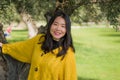 Pretty Asian woman in city park - lifestyle portrait of young beautiful and happy Japanese girl playful by a tree enjoying Royalty Free Stock Photo