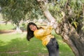 Pretty Asian woman in city park - lifestyle portrait of young beautiful and happy Japanese girl playful by a tree enjoying Royalty Free Stock Photo