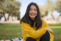 Pretty Asian woman in city park - lifestyle portrait of young beautiful and happy Japanese girl sitting on green grass cheerful Royalty Free Stock Photo