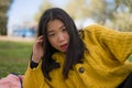 Pretty Asian woman in city park - lifestyle portrait of young beautiful and happy Japanese girl sitting on green grass cheerful Royalty Free Stock Photo