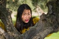 Pretty Asian woman in city park - lifestyle portrait of young beautiful and happy Korean girl playful by a tree enjoying enjoying Royalty Free Stock Photo