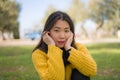 Pretty Asian woman in city park - lifestyle portrait of young beautiful and happy Korean girl sitting on green grass cheerful and Royalty Free Stock Photo