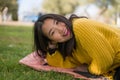 Pretty Asian woman in city park - lifestyle portrait of young beautiful and happy Korean girl sitting on green grass cheerful and Royalty Free Stock Photo