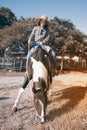 Pretty Asian woman cowgirl riding a horse outdoors in a farm. Royalty Free Stock Photo