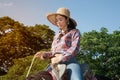 Pretty Asian woman cowgirl riding a horse outdoors in a farm. Royalty Free Stock Photo