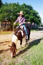 Pretty Asian woman cowgirl riding a horse outdoors in a farm.