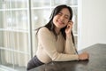 A pretty Asian woman enjoys listening to music through her headphones while sitting at a table Royalty Free Stock Photo