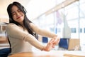 A pretty Asian woman enjoys the music and stretches her arms while relaxing at a table Royalty Free Stock Photo