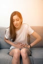 Asian woman holds her stomach with both hands. Stomach upset or pain during menstruation.