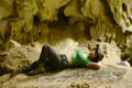 Pretty Asian woman lying on a rock with happiness and cheerfulness at Tham Hup Pa Tat.