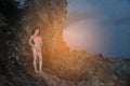 Pretty Asian woman in pink bikini posing on the stone of beach. Royalty Free Stock Photo