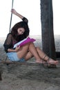 Pretty Asian woman reading on a swing .