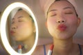 Pretty Asian woman cleaning her face - lifestyle portrait of young happy and beautiful Chinese girl at home applying makeup and Royalty Free Stock Photo