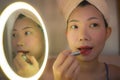 Pretty Asian woman with red lipstick- lifestyle portrait of young happy and beautiful Chinese girl at home applying makeup and Royalty Free Stock Photo